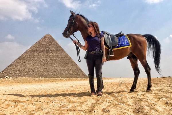 a woman and a horse posing for a photo in front of a pyramid in Egypt