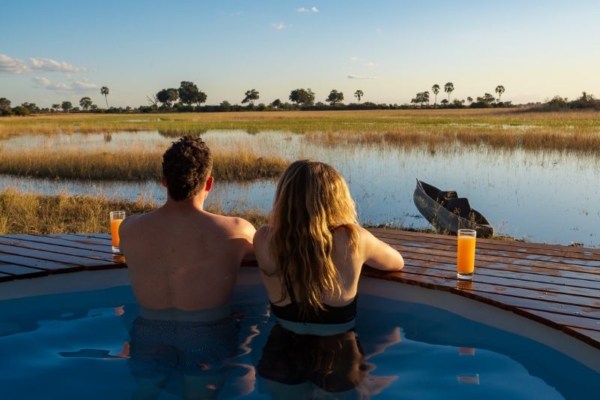 Couple in swimming pool looking over the Okavango Delta at Macatoo Lodge