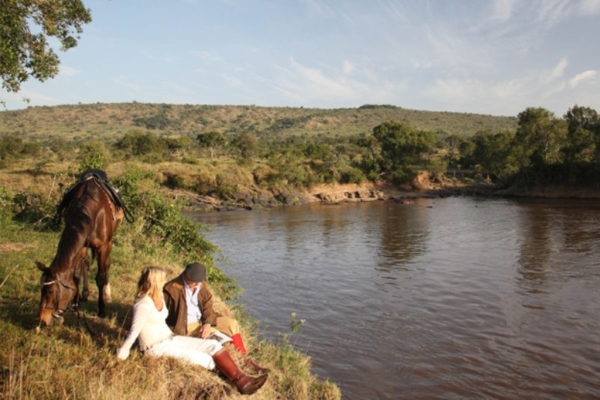 Couple sitting with horse next to river