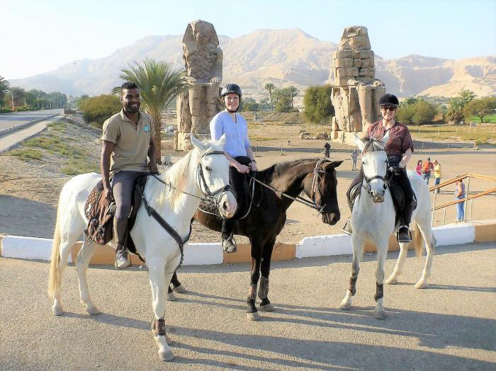 horse riders posing for a photo with horses in Colossi of Memnon, Egypt