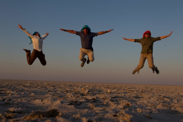 Three people jumping high arms open in salt pans