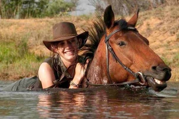 Smiling woman on horseback swim