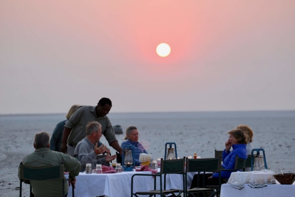 People sitting around a camp table with pink sunset