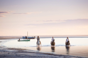 Girls riding horses bareback in ocean
