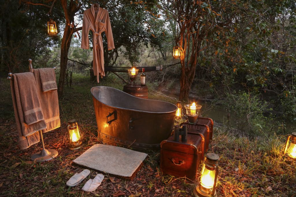 Copper bathtub in the middle of the forest with lanterns