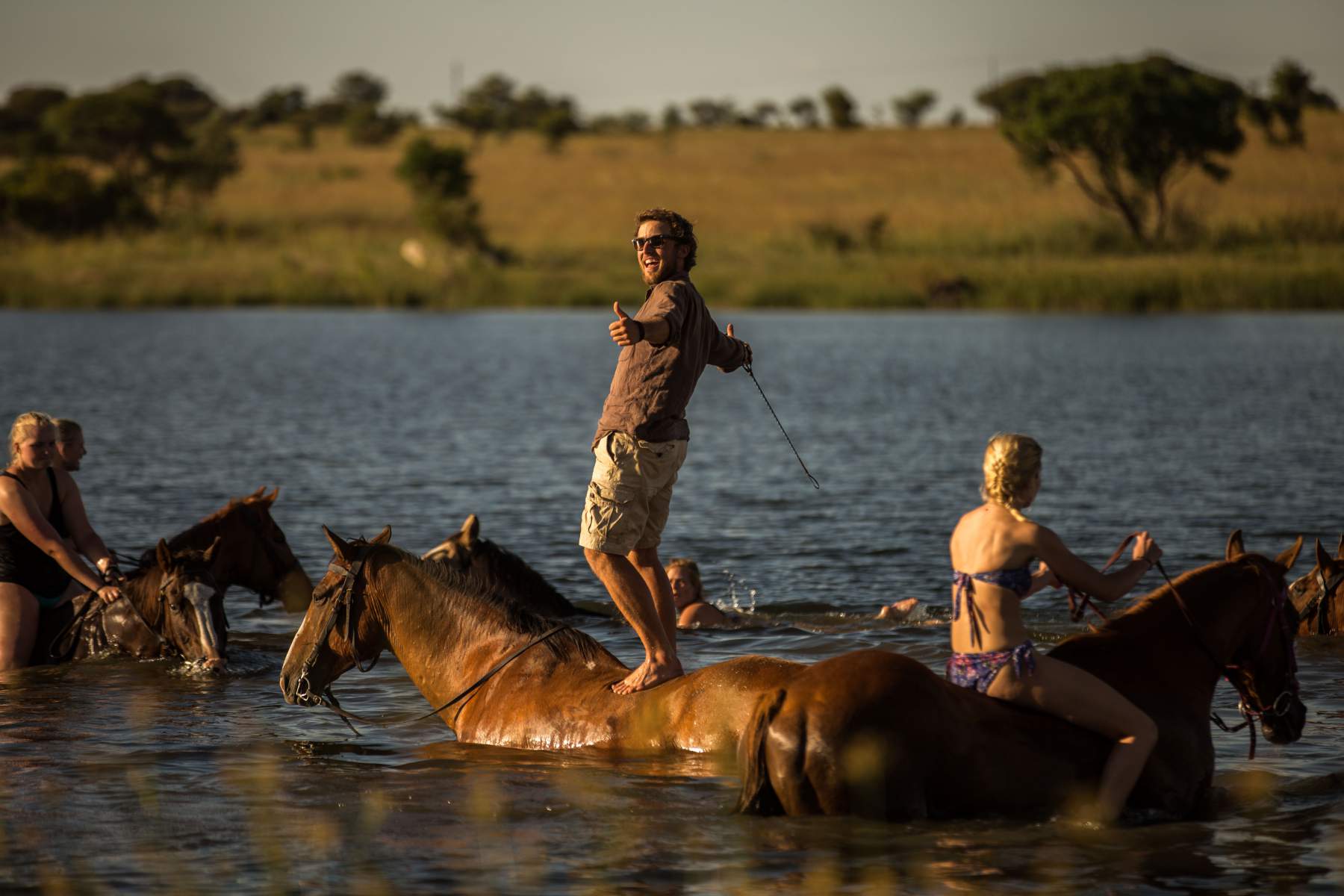A group horseriding in the river
