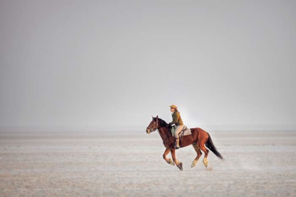 Horse rider galloping on salt pan