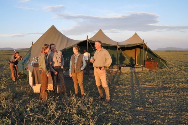 People having drinks in front of safari tent