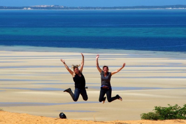 girls jumping in air with ocean behind them