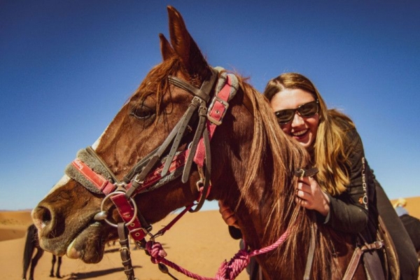 Smiling girl on horse in desert