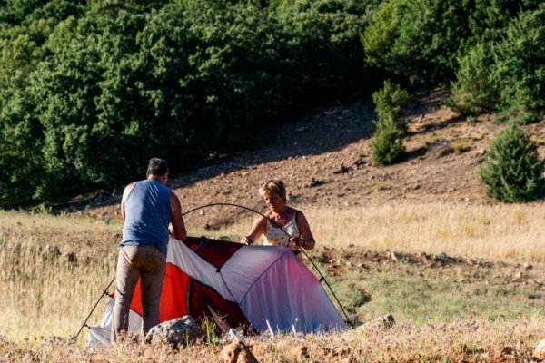 Two people setting up red tent
