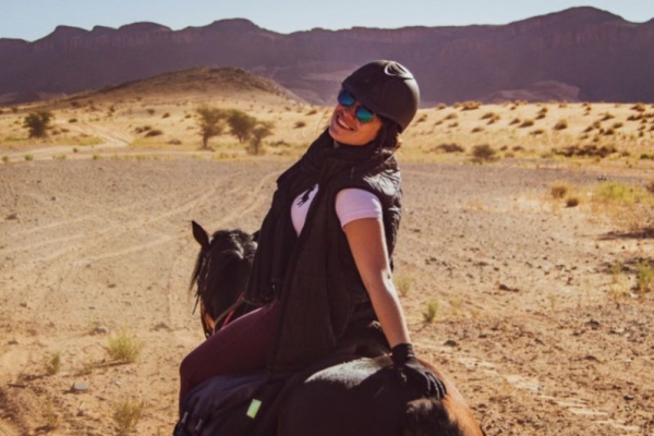 Smiling girl on horseback in desert