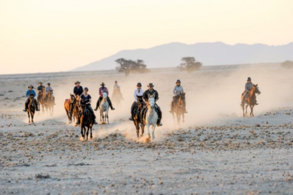 Horse riders galloping in the Namib Desert