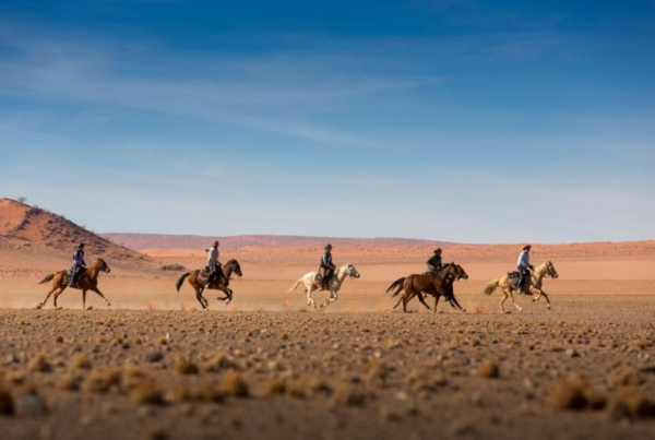 Horse riders galloping in the Namib Desert