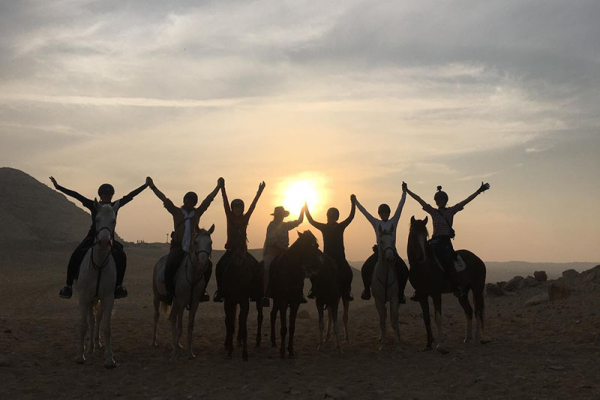 A group of riders posing at sunset