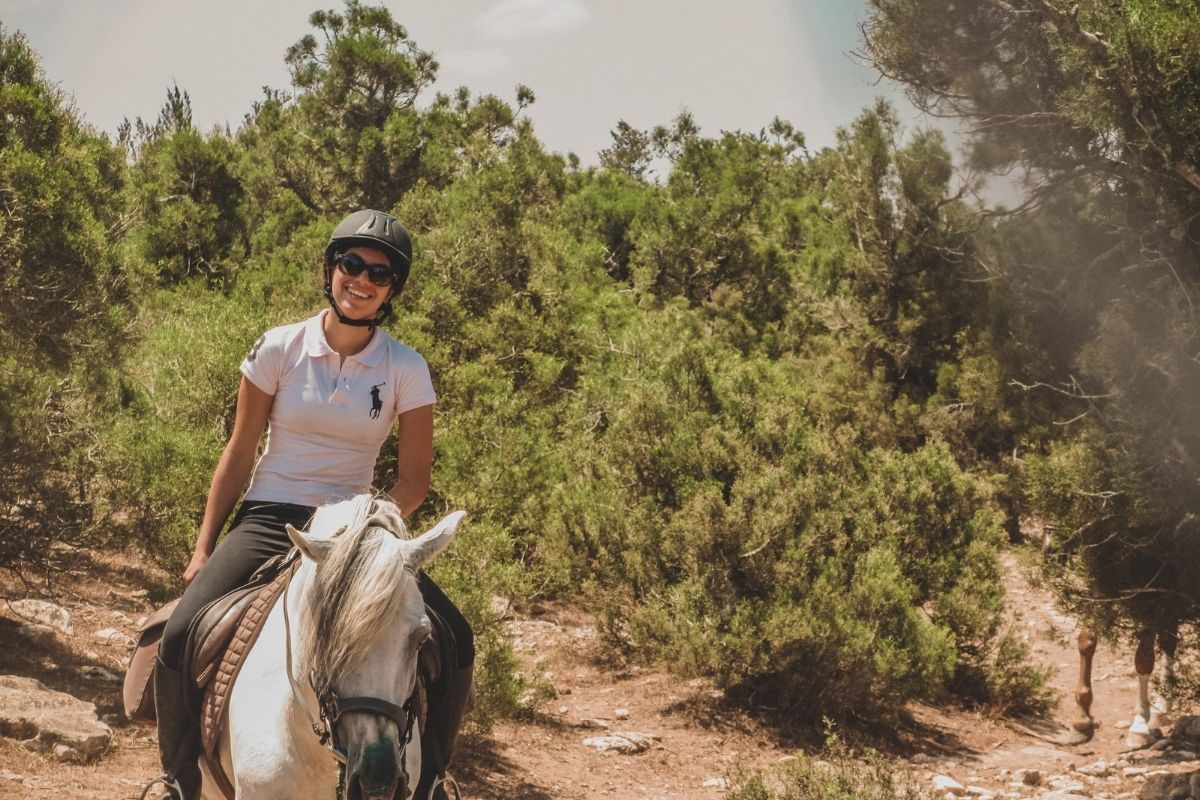 girl on a grey horse riding through bushes in essaouira