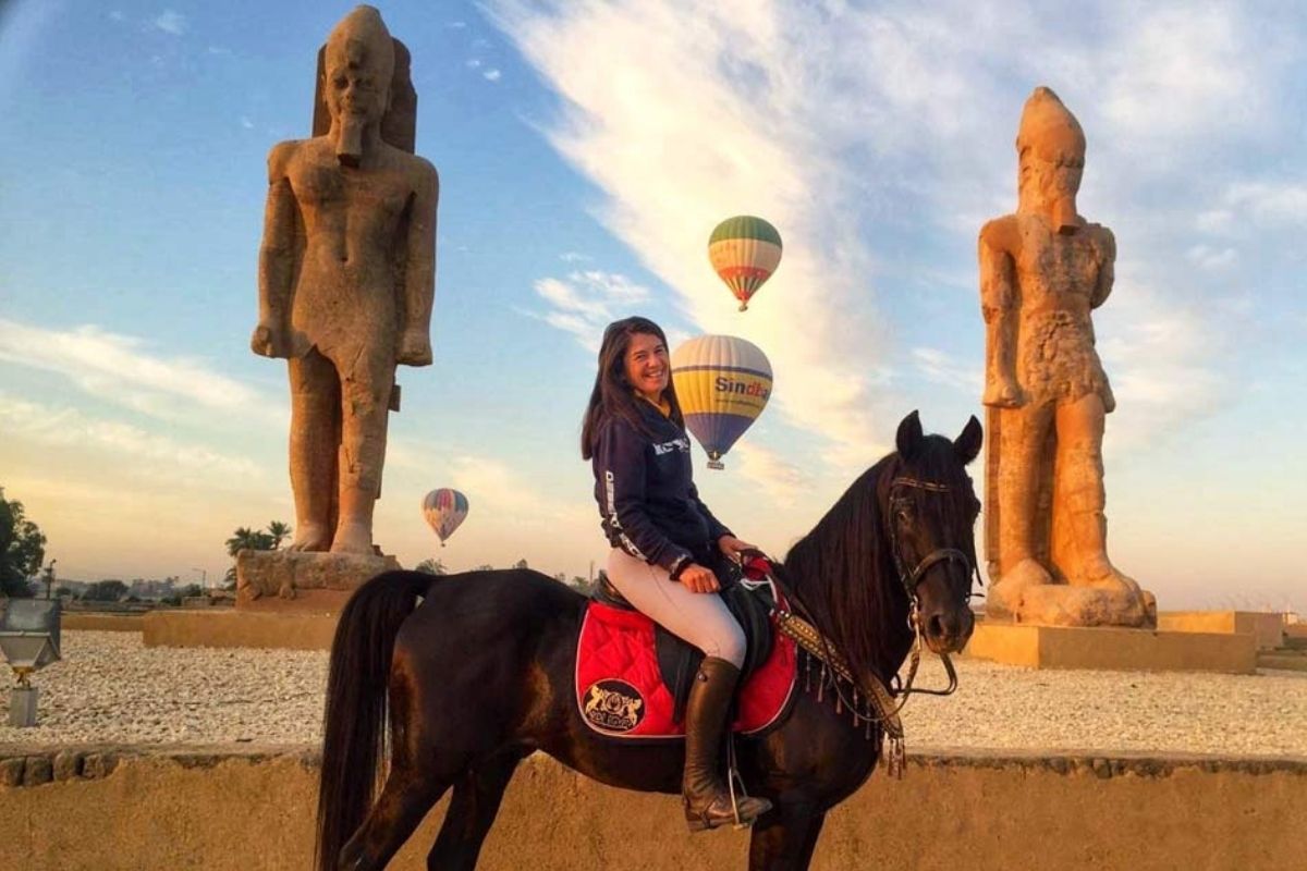 lady riding dark bay horse standing in front of statues on Pharoah's in egypt with hot air balloons in the background
