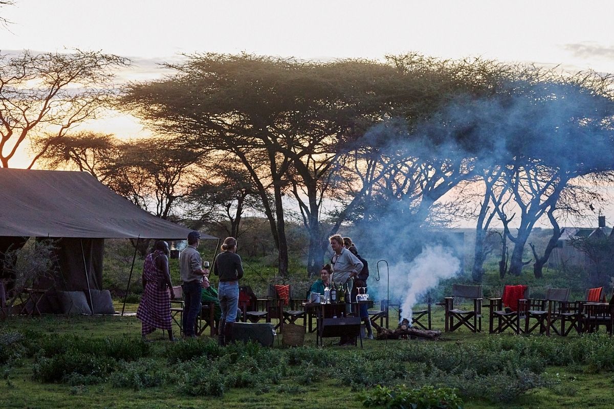 mobile camp with people near the fire at sunset