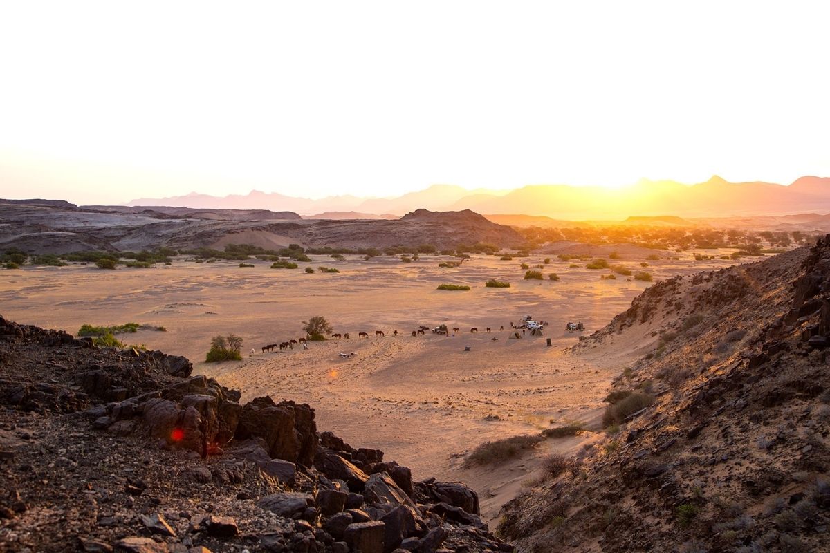 view of camp from the top of a hill overlooking the desert below with horses eating