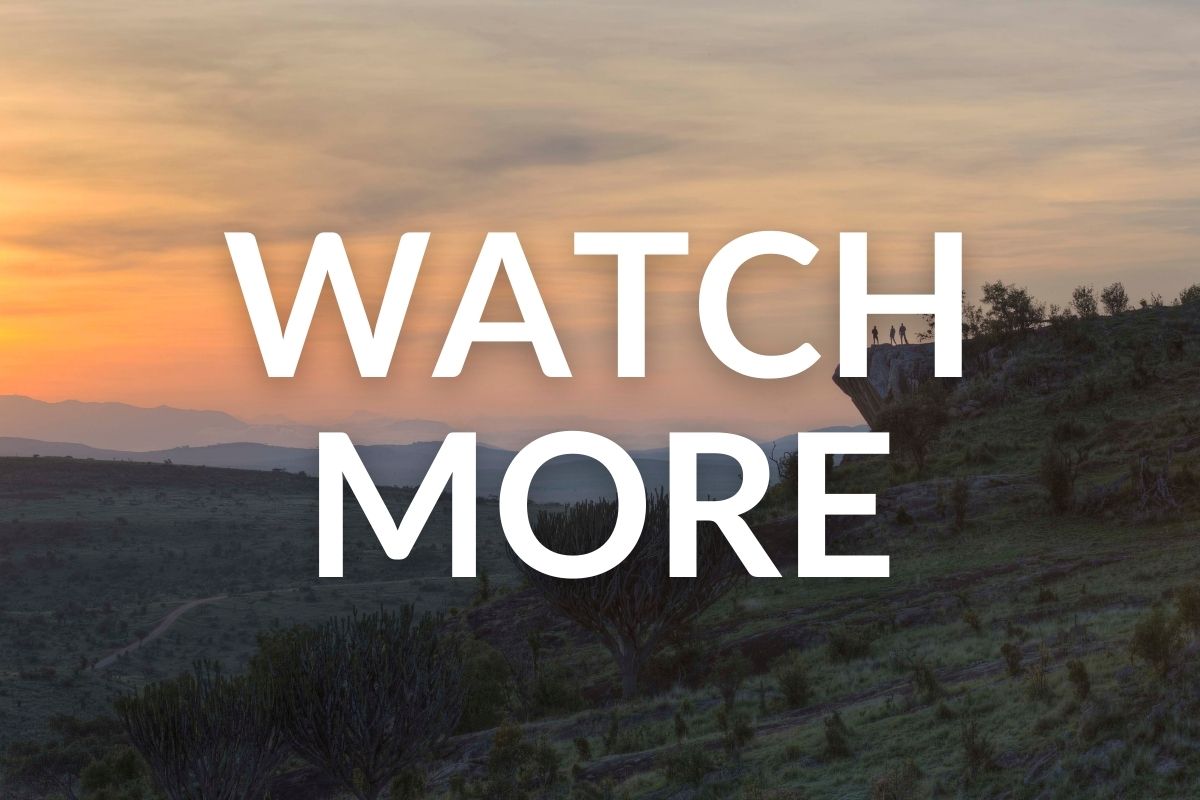 people standing on the edge of a rock overlooking the plains below in kenya
