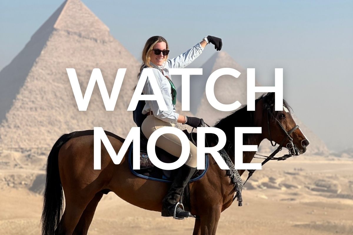 woman on a bay horse holding her hand above one of the pyramids in egypt from a distance